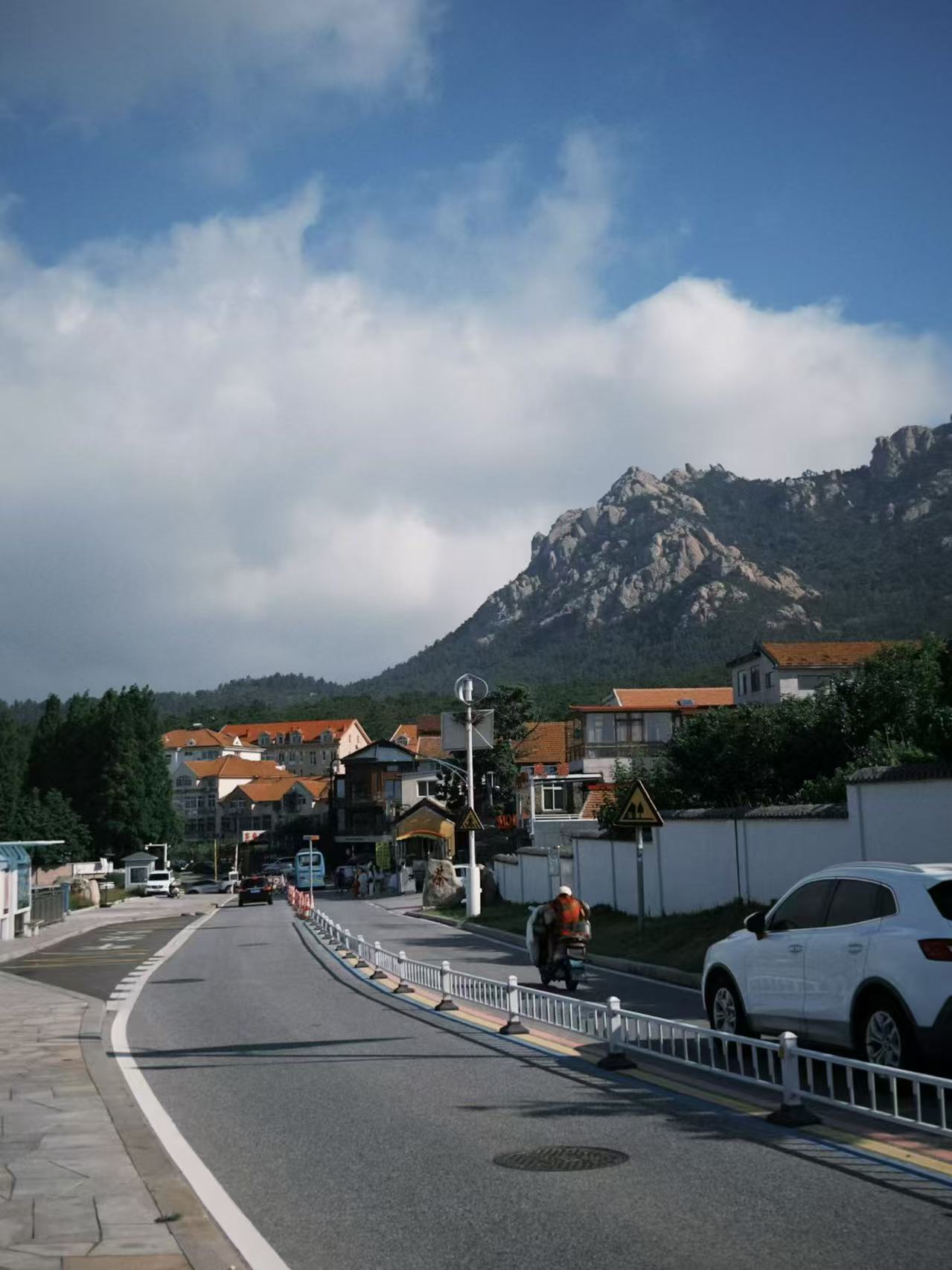 青岛海边山路，远处有山和红顶房屋